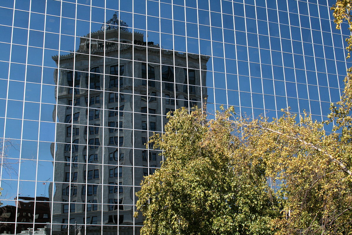 Reflexion eines neoklassizistischen Wolkenkratzers in der verglasten Vorhangfassade eines moderneren. Grand Rapids, Michigan.