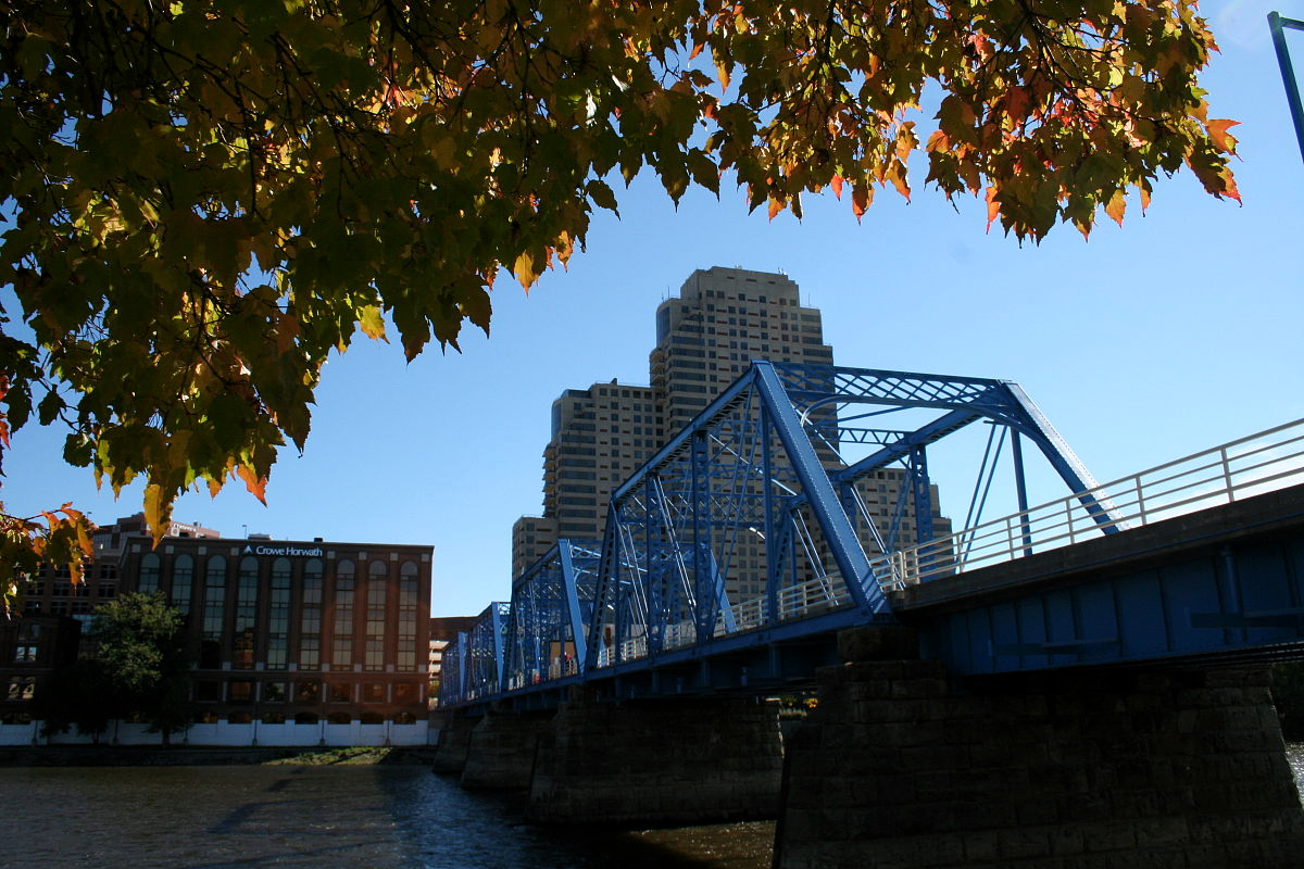 Blaue Brücke über den Grand River mit Skyscrapern und herbstlichem Laub. Grand Rapids, Michigan.